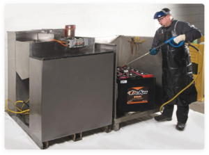 Employee watering industrial batteries with safety equipment on