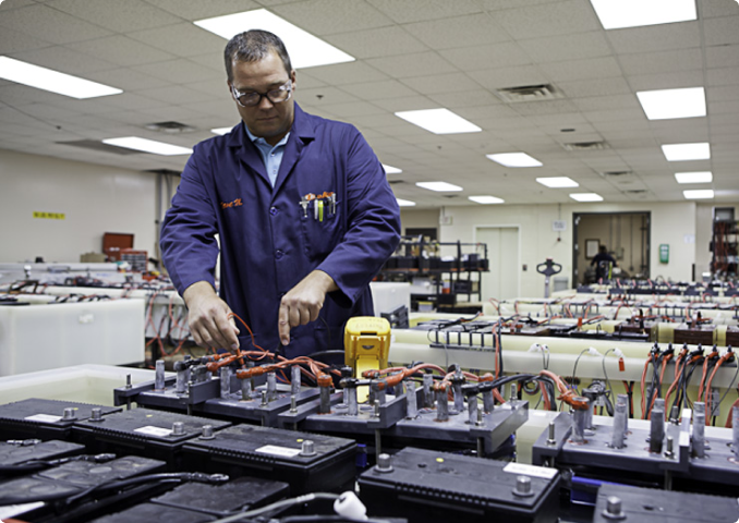 Employee performing battery maintenance service on industrial batteries