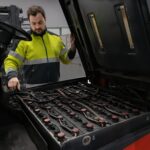 warehouse working inspecting low performing forklift battery