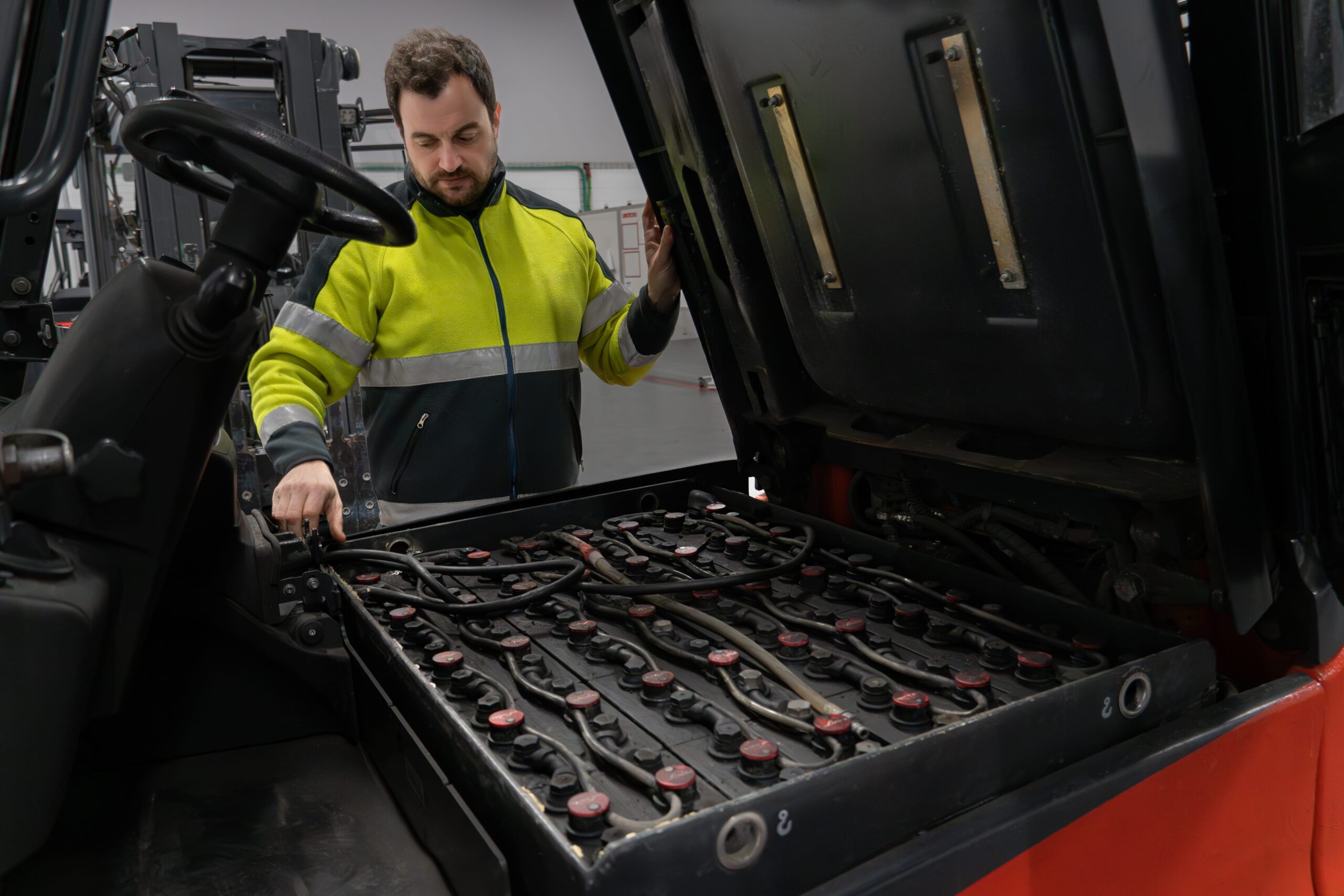 warehouse working inspecting low performing forklift battery